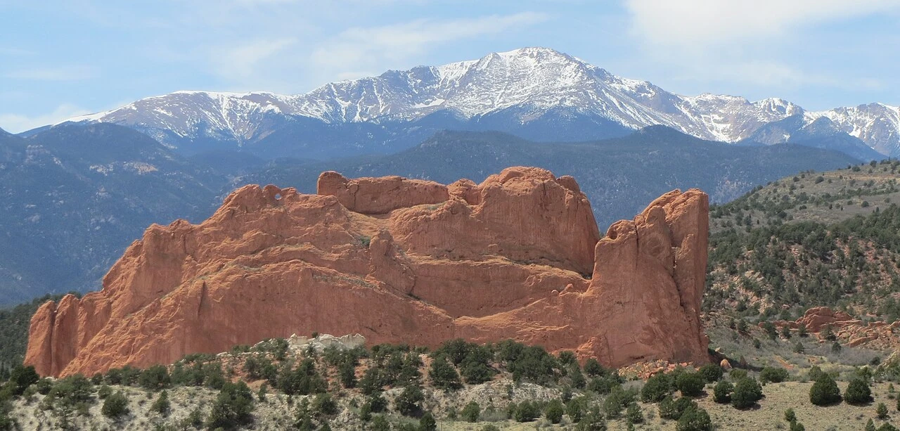 Red sandstone formations at Garden of the Gods with Pikes Peak behind them in Colorado Springs