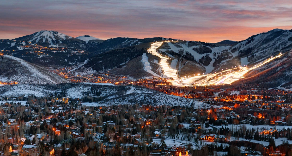 Park City, Utah, with snow-covered mountains and illuminated ski runs at dusk